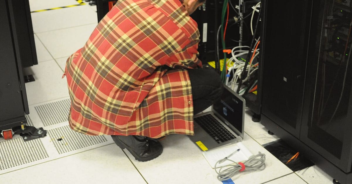 Technician with laptop working on server rack at NERSC